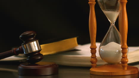 Sand-flowing-through-hourglass-beside-gavel-and-bible