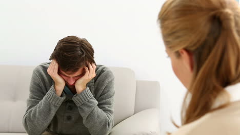 Young-man-sitting-on-sofa-talking-to-his-therapist