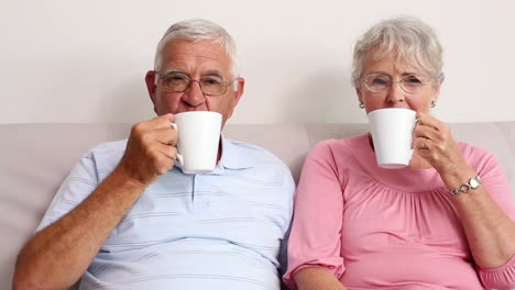 Happy-senior-couple-drinking-coffee-on-the-couch