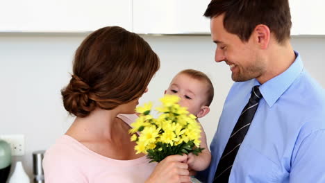 Father-surprising-mother-holding-baby-with-yellow-flowers