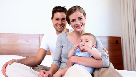 Glückliche-Eltern-Sitzen-Mit-Ihrem-Kleinen-Sohn-Im-Bett
