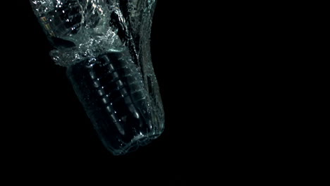 Plastic-bottle-falling-in-water-on-black-background