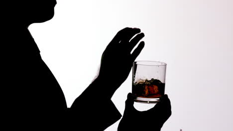 Silhouette-of-businessman-putting-ice-in-glass-of-whiskey