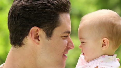 Happy-father-holding-his-baby-girl-in-the-park