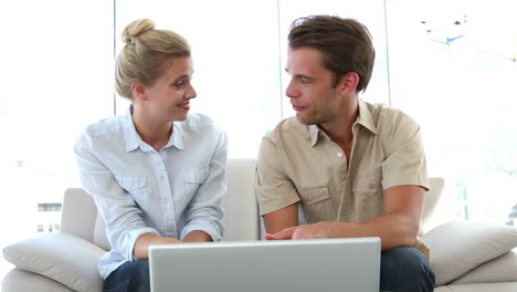 Couple-sitting-on-couch-looking-at-laptop