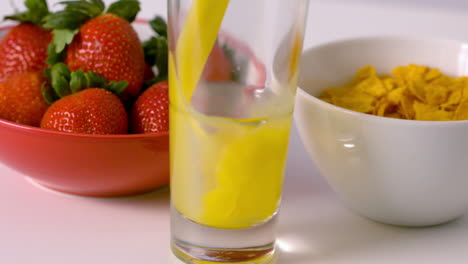 Orange-juice-pouring-into-glass-at-breakfast-table