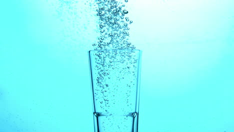 Bubbles-rising-from-glass-submerged-in-blue-water
