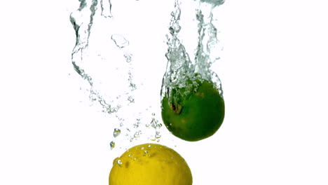 Lime-and-lemon-plunging-into-water-on-white-background