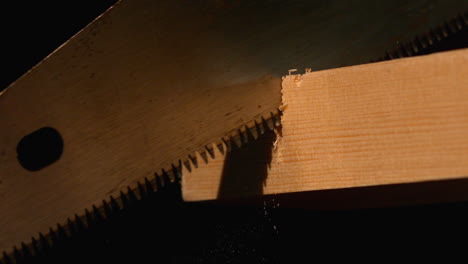 Saw-cutting-through-wood-on-black-background