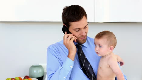 Businessman-holding-his-baby-and-talking-on-the-phone