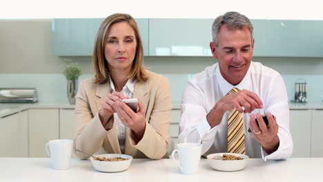 Couple-having-breakfast-and-texting-before-work-