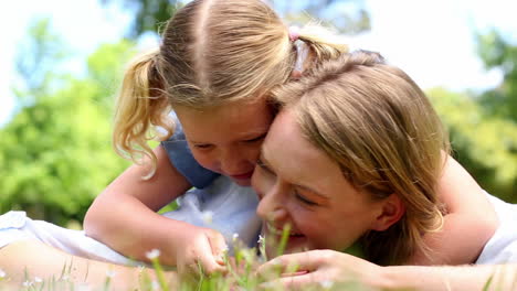 Glückliche-Mutter-Liegt-Mit-Ihrem-Kleinen-Mädchen-Im-Park-Auf-Dem-Gras