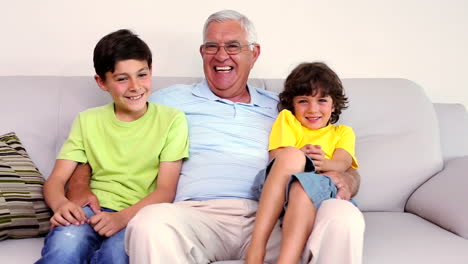 Senior-man-sitting-on-couch-with-his-grandsons