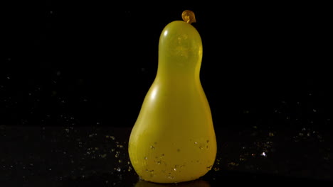 Yellow-water-balloon-falling-on-black-background