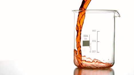 Orange-liquid-pouring-into-beaker