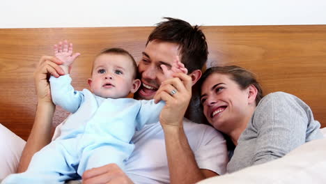 Glückliche-Eltern-Liegen-Mit-Ihrem-Kleinen-Sohn-Im-Bett