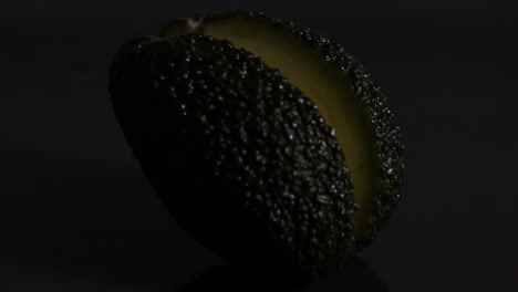 Avocado-falling-and-halving-against-black-background