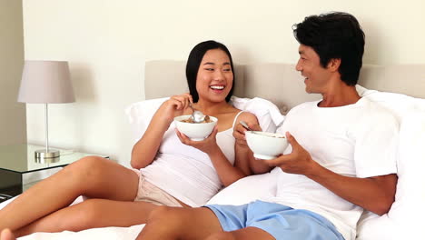 Couple-eating-bowls-of-cereal-in-bed