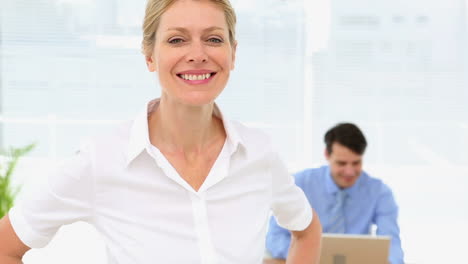 Businesswoman-smiling-at-camera-with-colleague-behind-her