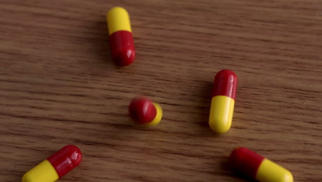 Pills-falling-onto-wooden-table