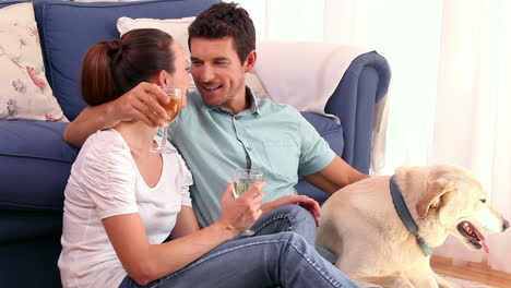 Feliz-Pareja-Sentada-En-El-Suelo-Bebiendo-Vino-Con-Su-Perro-Mascota