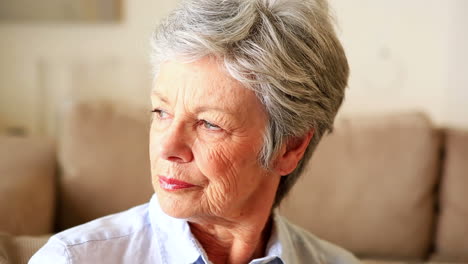 Unhappy-senior-woman-sitting-on-couch