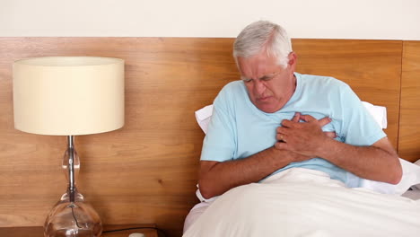 Senior-man-sitting-in-bed-having-a-heart-attack