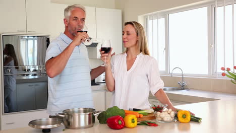 Happy-couple-drinking-red-wine-together-while-making-dinner