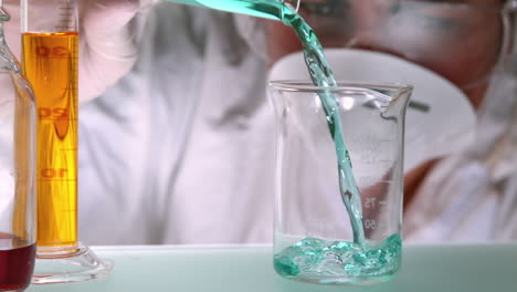 Scientist-pouring-teal-liquid-into-beaker