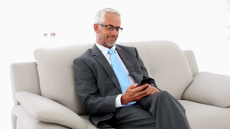 Businessman-sending-a-text-on-the-couch