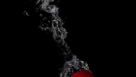 Tomato-falling-in-water-on-black-background