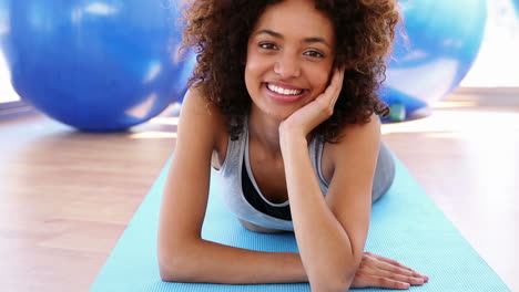 Smiling-woman-lying-on-exercise-mat