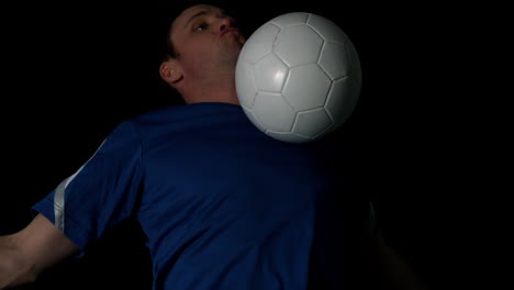 Footballer-controlling-the-ball-with-his-chest-on-black-background