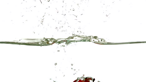 Red-apple-plunging-into-water-on-white-background