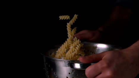 Hands-tossing-pasta-in-colander
