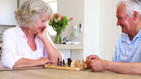 Senior-couple-sitting-at-table-playing-chess