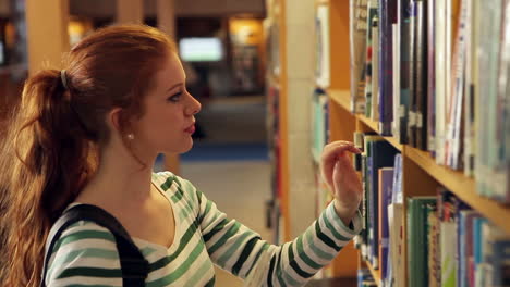 Estudiante-Concentrado-Recogiendo-Un-Libro-En-La-Biblioteca