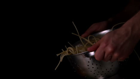 Hands-tossing-spaghetti-in-colander