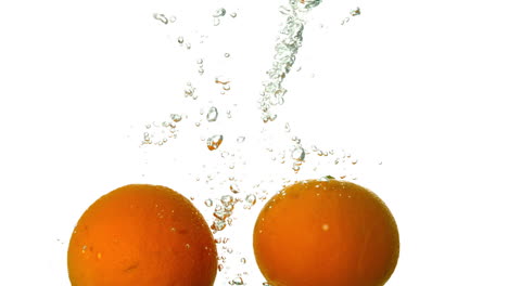 Oranges-plunging-into-water-on-white-background