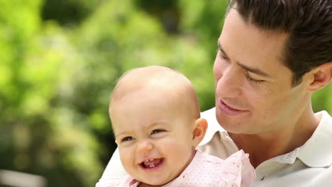 Padre-Feliz-Sosteniendo-A-Su-Niña-En-El-Parque