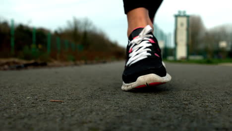 Cerca-De-Los-Pies-De-Una-Mujer-Corriendo-Por-El-Camino