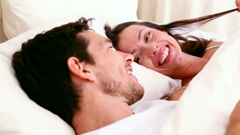 Happy-couple-lying-in-bed-chatting
