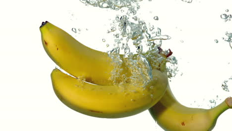 Bananas-plunging-into-water-on-white-background