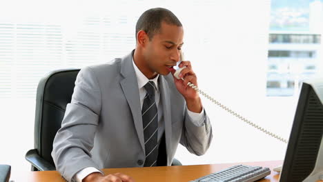 Businessman-working-at-his-desk-and-talking-on-phone