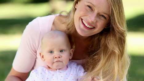 Happy-mother-holding-her-baby-girl-in-the-park