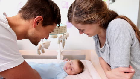 Happy-parents-watching-over-baby-son-in-crib-