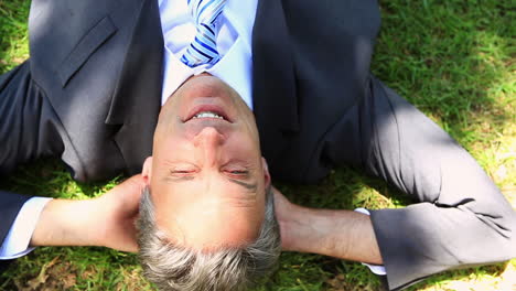 Happy-businessman-lying-on-the-grass