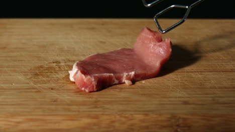 Pork-chop-falling-onto-wooden-table