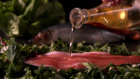 Olive-oil-pouring-over-fresh-trout-fillet-on-a-bed-of-leaves