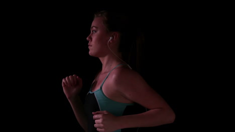 Woman-jogging-in-blue-and-black-top-while-listening-to-music